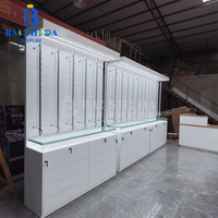 Vitrine murale moderne en bois blanc sur mesure avec éclairage LED et comptoir en verre verrouillable pour magasin d'optique, présentoir à lunettes