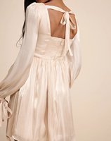 Robe mini à manches bouffantes en tissu brillant couleur champagne, dos noué, décolleté en cœur et corsage ajusté avec bonnets intégrés.