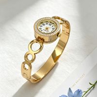 Montre bracelet pour femme à cadran rond incrusté de diamants, motifs ajourés multiples, bracelet en acier titane doré brillant