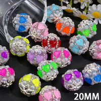 Strass en forme de cœur de couleur fluorescente, associés à un pendentif en métal argenté en forme de fleur et à une chaîne de perles demi-perles.