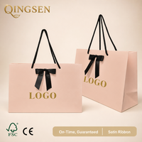 Sac shopping en papier rose personnalisé OEM avec nœud en ruban de satin noir, impression de logo et poignées torsadées pour boutique de détail