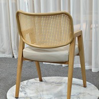 Chaise de salle à manger à bras angulaires avec dossier en rotin suspendu et assise rembourrée sur structure à grain clair pour salle de bain et atelier