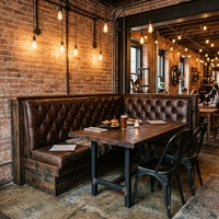 Ensemble de banquettes de restaurant contemporain de luxe avec canapé en cuir capitonné crème et table en marbre blanc avec chaises en velours