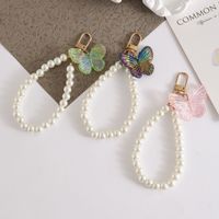 En gros, Porte-clés élégant papillon imitation perle, Chaîne de téléphone papillon en résine tendance, Bracelet de poignet à perles, Breloque de sac pour femmes