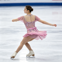 Robe de patinage artistique rose poudré à manches volantées, col en maille, nœud au dos, strass appliqués pour la compétition et la performance