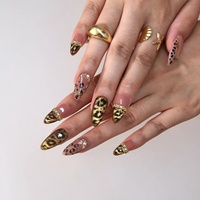 Ongles à presser en acrylique de luxe motif léopard, base rose nude, ligne métallique dorée, strass irisés, forme amande, ongles élégants et audacieux