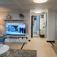 Maison modulaire préfabriquée moderne avec large porche couvert, balustrade et porte d'entrée en verre pour chambre d'amis dans la cour