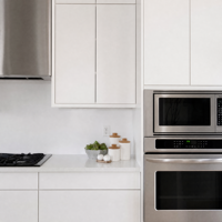 Meubles de cuisine modernes blancs à panneaux plats avec grand îlot, appareils électroménagers intégrés et design minimaliste en open space