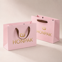 Sacs en papier rose personnalisés haut de gamme avec logo estampé or et poignée en ruban pour emballage de bijoux et cosmétiques HONPAK