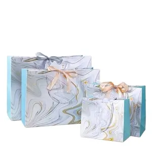 Mini petit sac en papier cadeau avec logo personnalisé pour bijoux de luxe dans la boutique de vêtements avec ruban et nœud papillon