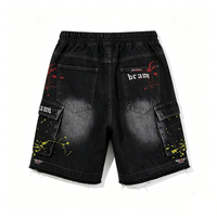 Shorts cargo vintage délavés à dégradé noir, avec détails éclaboussés de peinture, fermeture éclair, poches utilitaires et ourlet effiloché.