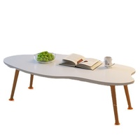 Table basse moderne et simple avec pieds en bois massif et plateau en panneau de densité, forme irrégulière, idéale pour les petits appartements et salons.