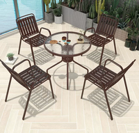 Ensemble de salle à manger d'extérieur moderne et durable de couleur marron avec table ronde en verre ondulé et structure en fer pour meubles de jardin et de terrasse