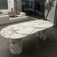 Table à manger ovale en marbre élégante et moderne, fabriquée à la main par Cammy Stone, avec finition Calaeatta blanche, pieds semi-ronds, pour la maison et l'hôtellerie