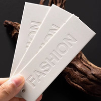 Étiquettes suspendues personnalisées en papier texturé gaufré pour vêtements de luxe discrets, idéales pour les marques de prêt-à-porter minimalistes haut de gamme