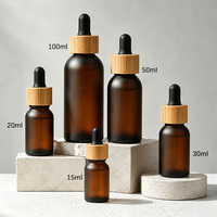 Bouteille en PET givrée marron incassable de capacités variées avec couvercle en bambou authentique pour l'emballage de sérums et d'huiles essentielles