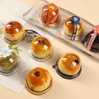 Une pâtisserie au jaune d'œuf transparente en forme de blister rond en plastique, avec un macaron doré et une pâtisserie à la crème pâtissière