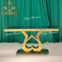Tables rectangulaires romantiques en acier inoxydable avec base double croisée dorée en forme de cœur et plateau transparent pour hôtels, restaurants et banquets de mariage