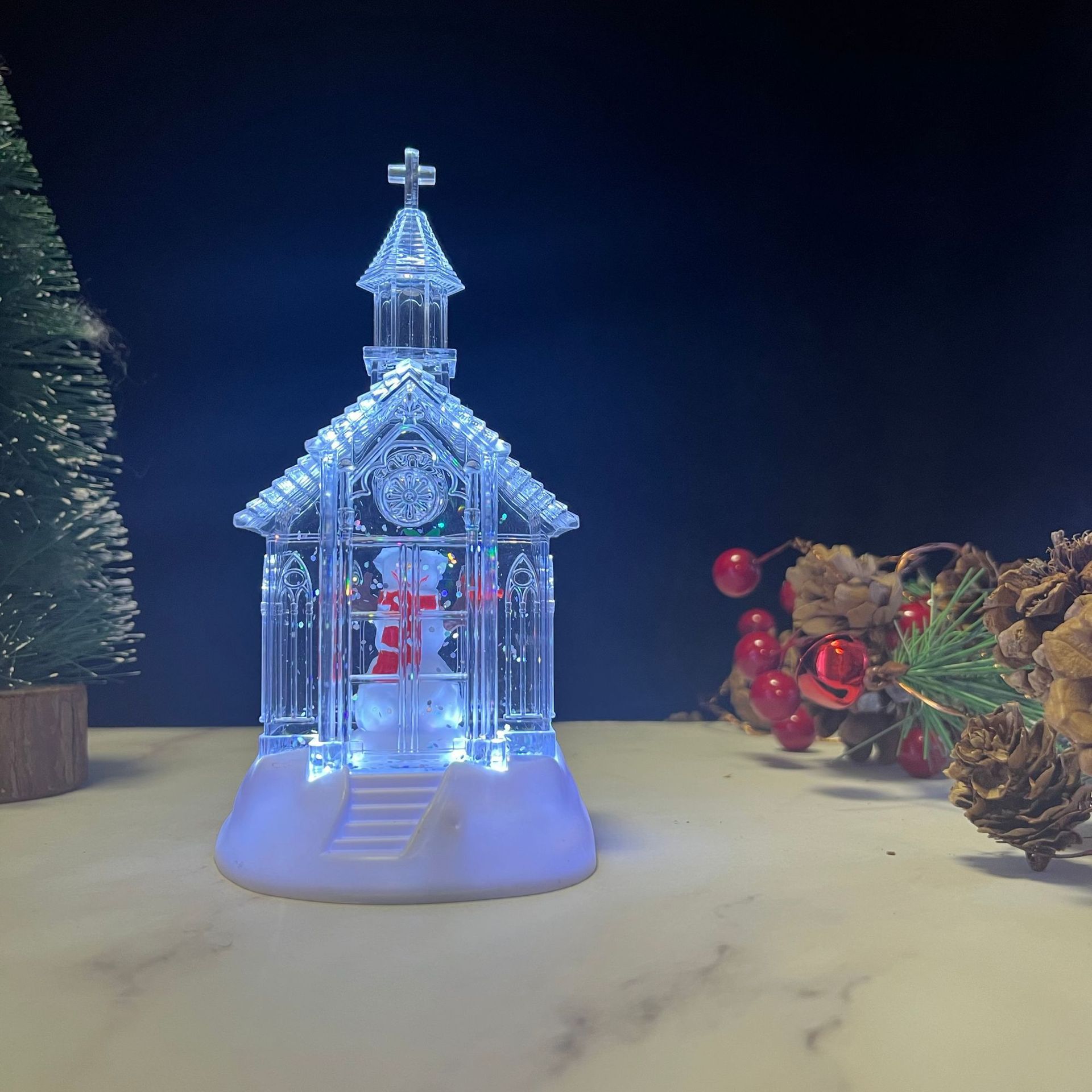 Iglesia con muñeco de nieve transparente lleno de agua.