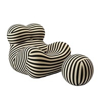 Fauteuil de salon sculptural en mousse moulée monobloc, design enveloppant, avec ottoman en tissu rayé