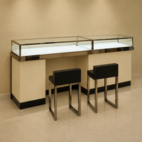Comptoir de consultation VIP pour bijoux de luxe, îlot de présentation en verre LED avec cadre en acier inoxydable poli et deux tabourets noirs