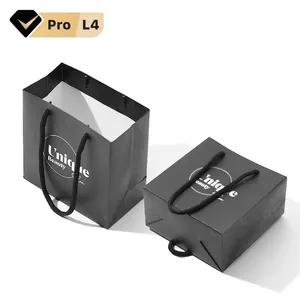 كيس ورقي أسود بطباعة مخصصة يمكنك وضع شعارك عليه حقيبة هدايا ورقية للتسوق مزودة بيد مسك لتعبئة الملابس