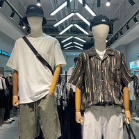 Boutiquede vêtements d'affairesélégants avecaffichage en métalnoir, cintres linéaires et unités de rangement à plusieurs niveaux