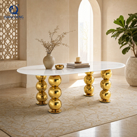 Table de banquet ovale de luxe pour hôtel, avec plateau en marbre blanc et pieds en acier inoxydable doré, pour événements et mariages.