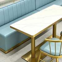 Table de restaurant en pierre frittée sur mesure avec structure métallique et sièges muraux adjacents pour hôtel et café