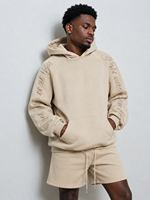 Sweat à capuche homme streetwear coupe ample en molleton de coton épais, avec motif graphique brodé beige personnalisé et manches brodées style script, tendance