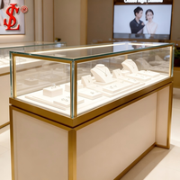 Vitrine de présentation de bijoux de luxe en verre doré, cadre en or brossé, éclairage LED, meuble de vente au détail, aménagement de boutique