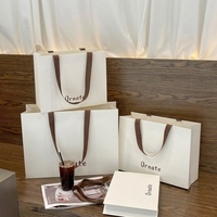 Sac fourre-tout en papier biodégradable blanc crème de luxe avec logo personnalisé, laminage mat, large ruban pour boutique de vêtements et de chaussures