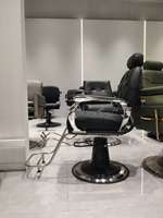 Fauteuil de barbier pliable en cuir synthétique noir, robuste, avec pompe hydraulique et repose-pieds réglable, pour salon commercial.