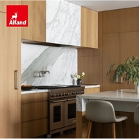 Cuisine moderne en placage de chêne blanc, définie par des veines de marbre spectaculaires, avec une île sculpturale en demi-cascade et une armoire de rangement en panneaux de marbre.