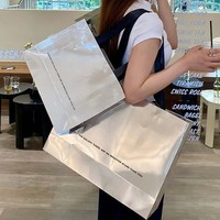 Sac en carton holographique argenté brillant de luxe avec logo noir personnalisé imprimé et poignée en ruban pour boutiques et commerces de détail