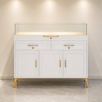 Vitrine de présentation de bijoux de luxe, laque blanche mate, quincaillerie dorée, dessus en verre trempé sans cadre, éclairage LED, tiroirs de rangement, portes