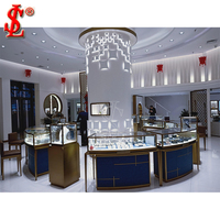 Vitrine de présentation de bijoux de luxe blanc laiteux, table en verre et métal or et noir avec éclairage LED pour mobilier de boutique de détail
