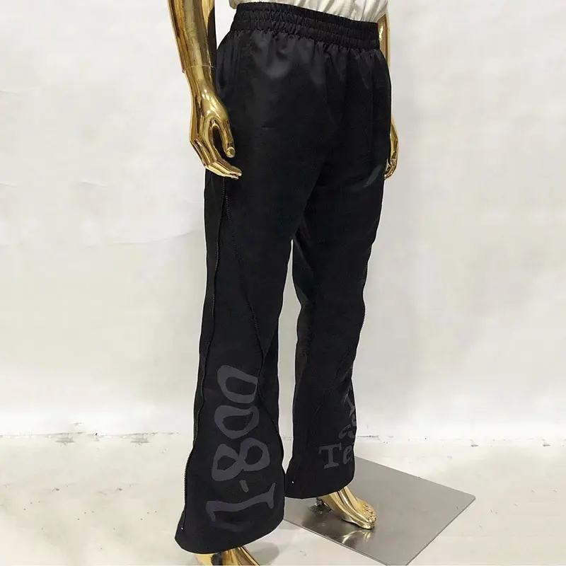 बड़े आकार के पुरुष कस्टम लोगो वाटरप्रूफ नायलॉन जिपर फ्लेयर्ड ट्राउजर ढीले स्ट्रीटवियर फिटनेस ट्रैक पैंट