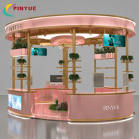 Kiosque de présentation de cosmétiques de luxe en or rose pour centre commercial, avec auvent LED ovale, comptoirs d'exposition incurvés, étagères en verre