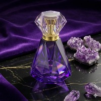 Flacon de parfum élégant carré de 50 ml en verre facetté avec finition irisée, bouchon doré, pulvérisateur à pompe, emballé dans un carton sérigraphié