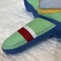 Petit avion bleu et vert, en forme de coussin décoratif