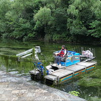 Bateau amphibie multifonctionnel pour la récolte et l'élimination des plantes aquatiques dans les zones humides et les réservoirs, avec coupe-roseaux.