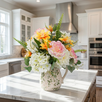 Künstlicher Strauß mit rosa Nelken und orangefarbenen Lilien, gemischtes weißes Hortensien-Kunstblumen-Set mit grüner Rankenoptik und cremefarbener Krugvase