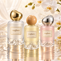 Flacon de parfum cylindrique de luxe en verre avec base sculptée en forme de montagne, bouchon en galet doré, sérigraphie, 30ml 50ml 100ml pour parfum