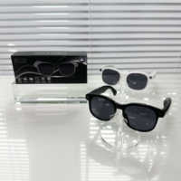 Lunettes intelligentes à monture en titane blanc et noir avec verres foncés sur présentoirs