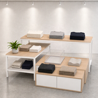Ensemble de table de présentation à niveaux en MDF et acier inoxydable avec pieds fins noirs et armoire grise sur mesure