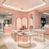 Ensemble de présentoirs de magasin de beauté rose, table d'îlot cosmétique à LED arquée, vitrine murale, équipements personnalisés
