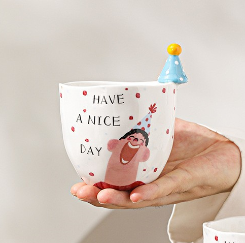 Le garçon dans un chapeau bleu tient une tasse