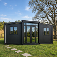 Maison conteneur pliable extensible noir mat avec panneaux en verre et portes doubles pour le glamping rural, le bureau de chantier