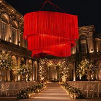Décoration de plafond suspendue en macramé rouge sur mesure à trois niveaux avec des pompons et des fleurs artificielles pour la réception d'hôtel, OEM